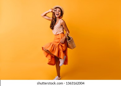 Gorgeous red-haired white woman dancing in studio. Dreamy girl in long skirt having fun on orange background. - Powered by Shutterstock