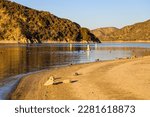 a gorgeous shot of the still lake waters with white and orange buoys in the water with lush green mountain ranges and sandy beaches at Silverwood Lake State Recreation Area in Hesperia California USA