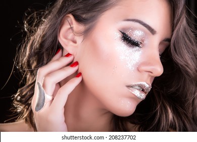 Gorgeous silver glitter make up on eyes and lips, beautiful brunette woman with medium length hair wearing a ring beauty studio shot