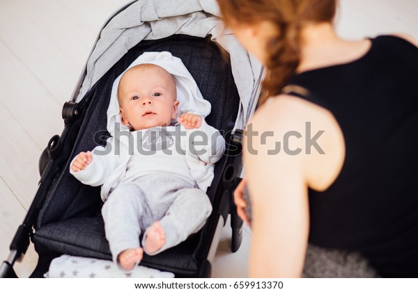 Gorgeous sporty\
mother calming down and speaking with her baby boy. Little cute\
baby smiling and looking at\
camera.