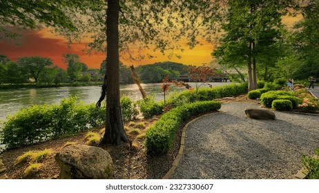 A gorgeous spring landscape along the Chattahoochee River with lush green trees, grass and plants and colorful flowers with powerful clouds at sunset at Ray’s on the River in Sandy Springs Georgia - Shutterstock ID 2327330607