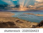 a gorgeous spring landscape at Lake Mead with vast blue water and majestic mountain ranges and boats and yachts docked in the marina with powerful clouds at sunset in Las Vegas Nevada USA