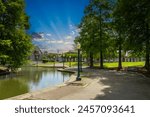 a gorgeous spring landscape at Louis Armstrong Park with lush green trees, plants and grass, a lake and powerful  clouds at sunset in New Orleans Louisiana USA