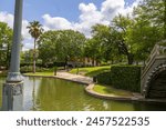 a gorgeous spring landscape at Louis Armstrong Park with lush green trees, plants and grass, a lake, blue sky and clouds in New Orleans Louisiana USA