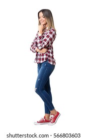 Gorgeous street style woman wearing jeans, plaid shirt and sneakers smiling looking down. Full body length portrait isolated over white studio background. 