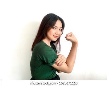 Gorgeous Strong Young Asian Woman With Green Shirt Showing Biceps And Smiling. Indonesian Girl Strong Concept.