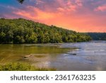 a gorgeous summer landscape along the Chattahoochee river with flowing water surrounded by lush green trees, grass and plants with powerful clouds at sunset in Atlanta Georgia USA	