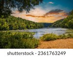 a gorgeous summer landscape along the Chattahoochee river with flowing water surrounded by lush green trees, grass and plants with powerful clouds at sunset in Atlanta Georgia USA	