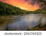 a gorgeous summer landscape along the Chattahoochee river with flowing water surrounded by lush green trees, grass and plants with powerful clouds at sunset in Atlanta Georgia USA	