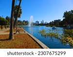 a gorgeous summer landscape at Echo Park Lake with people in swan shaped pedal boats on rippling blue water surrounded by lush green trees, grass and plants and blue sky in Los Angeles California USA
