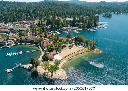 A gorgeous summer landscape at Lake Arrowhead village with boats and yachts on the rippling blue water, homes on the hillside with lush green trees in Lake Arrowhead California USA