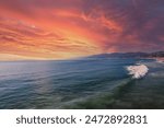 a gorgeous summer landscape at Santa Monica Beach with blue ocean water, rolling waves, mountains and powerful clouds at sunset in Santa Monica California USA