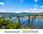 A gorgeous summer landscape at the Walnut Street Bridge with lush green trees and plants, blue sky and clouds over the Tennessee River in Chattanooga Tennessee USA