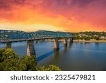 A gorgeous summer landscape at the Walnut Street Bridge with lush green trees and plants and powerful clouds at sunset over the Tennessee River in Chattanooga Tennessee USA