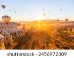 Gorgeous sunrise scenery of hot air balloons flying over Love valley with rock formations and fairy chimneys in Cappadocia Turkey