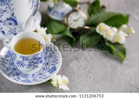 A gorgeous tea cup with green tea and jasmine blossoms.