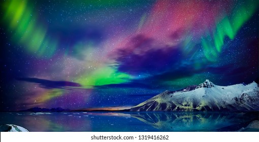  Gorgeous, unreal beautiful night view of the reflection of the northern lights in the water of the ocean and snow-capped mountains. Night Northern Lights is just an amazing sight. - Shutterstock ID 1319416262