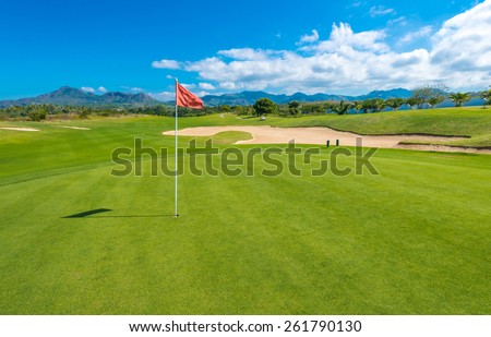 Gorgeous view at the beautiful golf course with sand bunker and red flag.