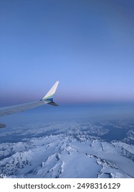 Gorgeous view from plan window over snow capped mountains during sunset