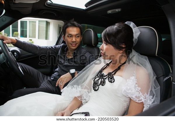 gorgeous wedding couple in car /groom  driving car,\
bride sitting. 