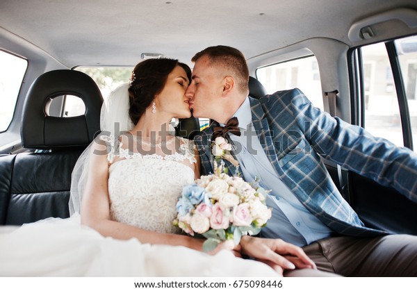 Gorgeous wedding couple\
kissing in a car.
