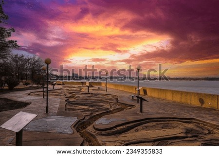 a gorgeous winter landscape along the Mississippi River at Mississippi River Park with flowing water and yellow grass with powerful clouds at sunset in Memphis Tennessee USA