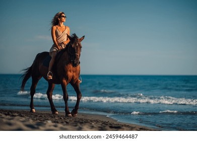 Gorgeous woman galloping on a horse on an ocean coast during a summer sunset. Young beautiful female with a horse in the rays of the sun by the sea. Looking at the sea horizon. - Powered by Shutterstock