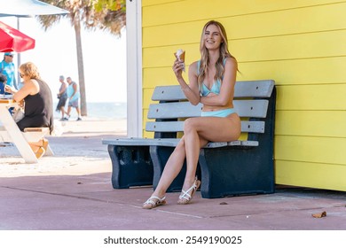 A gorgeous woman reclines on a sandy beach, her bikini accentuating her golden tan. She enjoys an ice cream cone, the sun's warmth embracing her, while waves gently whisper at the shore. - Powered by Shutterstock