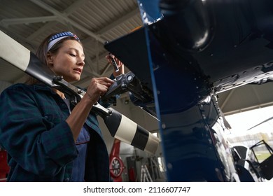 Gorgeous woman wearing uniform fixing the engine of the aircraft in hangar - Powered by Shutterstock