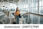 A gorgeous young Asian female tourist passenger is on an airport escalator, carrying her luggage, going to the airport check-in counter, traveling by plane. people and transportation concepts