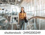 A gorgeous young Asian female tourist passenger is on an airport escalator, carrying her luggage, going to the airport check-in counter, traveling by plane. people and transportation concepts