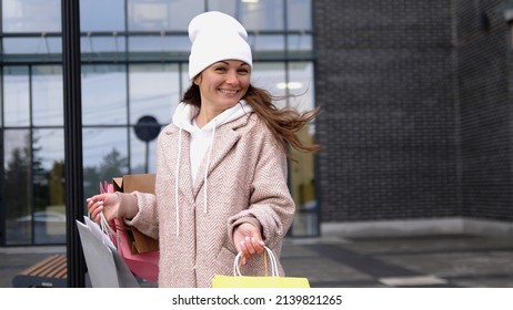 Gorgeous young happy woman with different bags walking in a city