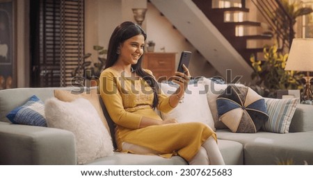 Gorgeous Young Indian Woman Making a Video Call on Her Smartphone at Home, Sharing Laughs and Gossip with Girfriends. Stunning Girl with Magnificent Smile talks to Her Boyfriend Online. Medium Shot