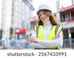 Gorgeous Young woman builder wearing safety gear smiles confidently at construction site in urban setting during daylight