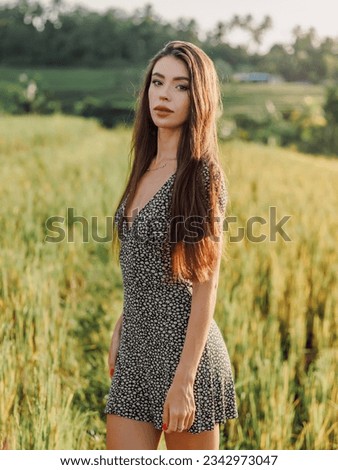Gorgeous young woman in dress on rise terraces in Bali with morning sunlight. Glamour lady at rice field