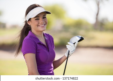 Gorgeous young woman holding a golf club and smiling