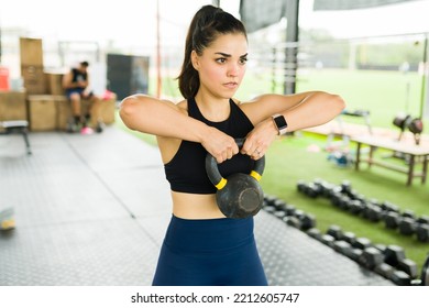 Gorgeous young woman lifting a kettlebell weight while exercising with a cross training routine - Powered by Shutterstock