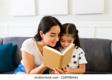 Gorgeous Young Woman And Little Girl Enjoying Reading A Beautiful Fairy Tale On A Children's Book At Home