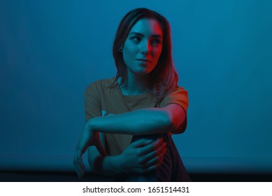 Gorgeous Young Woman Is Looking Aside, At A Red Light, On Light Blue Background. Close  Portrait.