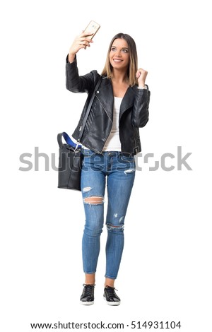 Gorgeous young woman in street style clothes taking selfie with mobile phone. Full body length portrait isolated over white background