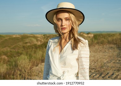 Gorgeous Young Woman In White Romantic Clothes On Summer Field Background. Yellow Grass, Blue Sky. Sunny Day. Blonde Model With Big Beautiful Eyes And Nice Lips. Calm And Balance. Fashionable Look  