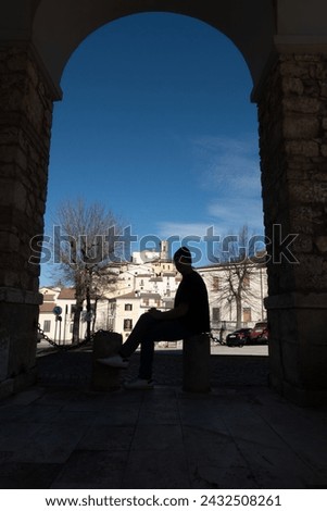 Goriano Sicoli, Italy Person sits on a stoop in sihouette under an arch with a view over this medieval hilltop town.