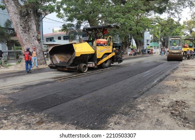 Gorontalo, October 5, 2022 : Asphalt Paver Machine And Truck. Road Construction Crew Apply The First Layer Of Asphalt. Hot Mix Asphalt Paving And Road Work - Flatten Out The Hot Asphalt Road With Road