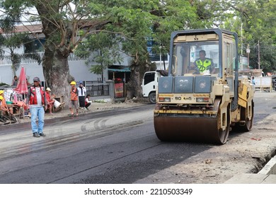 Gorontalo, October 5, 2022 : Asphalt Paver Machine And Truck. Road Construction Crew Apply The First Layer Of Asphalt. Hot Mix Asphalt Paving And Road Work - Flatten Out The Hot Asphalt Road With Road