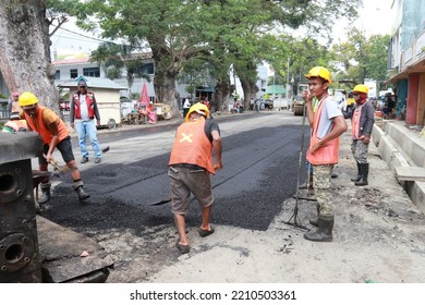 Gorontalo, October 5, 2022 : Asphalt Paver Machine And Truck. Road Construction Crew Apply The First Layer Of Asphalt. Hot Mix Asphalt Paving And Road Work - Flatten Out The Hot Asphalt Road With Road