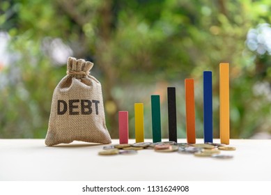 Gorvernment or public  national debt concept : Color wood bar graph, coin and a debt bag on a table, depicts the government collects taxes less than spending, the difference is called deficit or debt