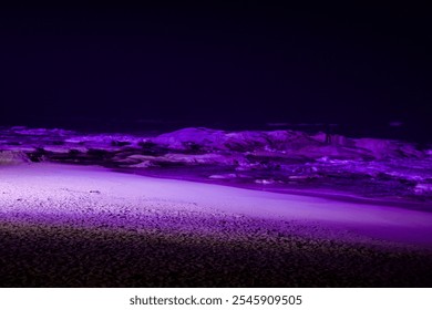 Goseong County, South Korea - November 3, 2024: Ayajin Beach's rocky shoreline and sandy stretch glow under vivid purple lights, illuminating the textures of the sand and stones against the dark sea. - Powered by Shutterstock