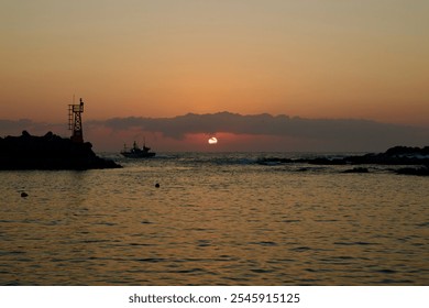 Goseong County, South Korea - November 3rd, 2024: A fishing boat departs Muam Port at sunrise, silhouetted against a soft, glowing sky as the sun emerges from the horizon, casting light over waters. - Powered by Shutterstock