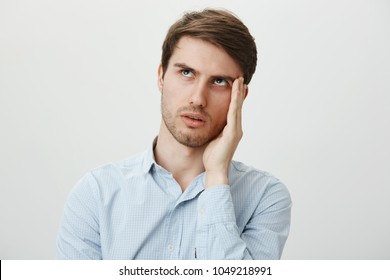 Gosh, So Annoying, Hope She Would Not Talk To Me. Portrait Of Bothered Handsome Young Man In Casual Shirt Holding Palm Near Cheek To Hide Face From Clingy Ex Girlfriend, Rolling Eyes From Contempt