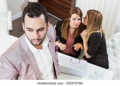 Gossip girls at office, handsome businessman portrait and gossip girls out of focus in background.